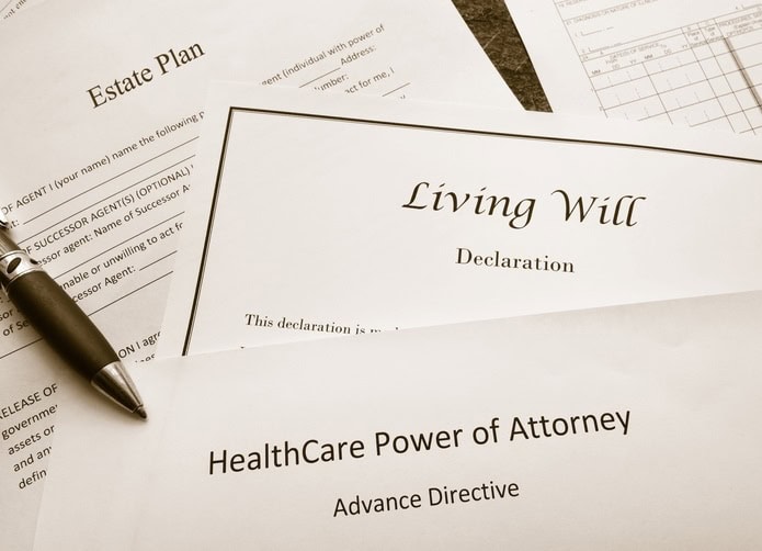 Close-up of legal documents labeled “Living Will,” “Estate Plan,” and “Healthcare Power of Attorney,” with a pen resting on the papers.