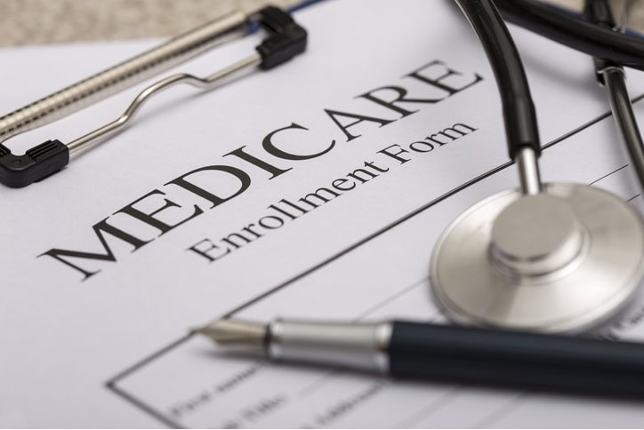 Close-up of a “Medicare Enrollment Form” on a clipboard with a stethoscope and pen resting on top.